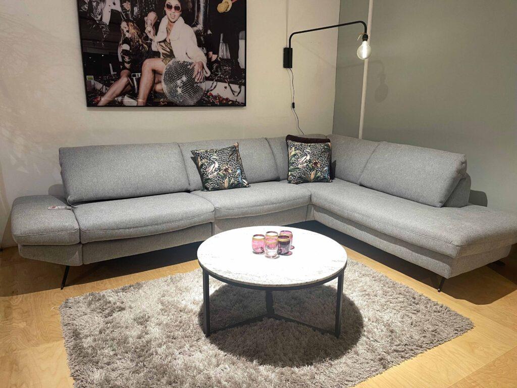 Wohnzimmermöbel aus massiver Eiche, bestehend aus einem niedrigen TV-Board mit Schubladen, einem Hängeschrank mit Glaselement, und einem offenen Wandregal mit versetzten Fächern. Auf dem TV-Board steht ein kleiner Fernseher, eine schwarze Schale mit grünen Äpfeln sowie zwei weiße Vasen. Dekorationsartikel befinden sich auch im Wandregal.