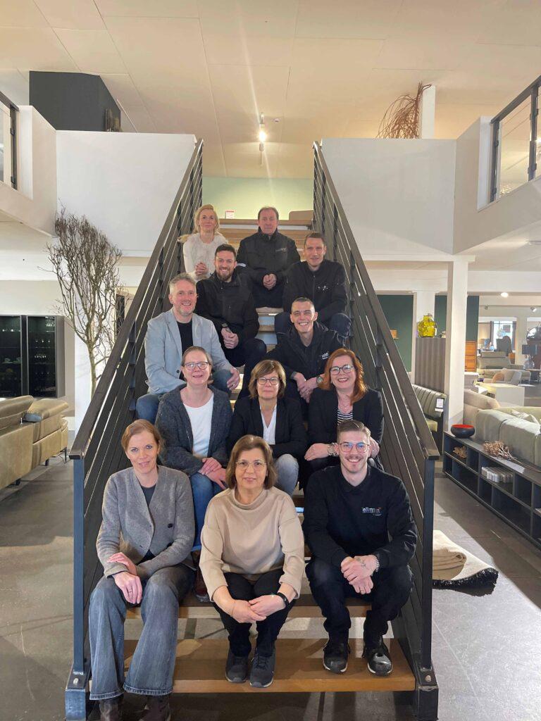Das Team Tellmann sitzt auf der Treppe des Möbelhauses